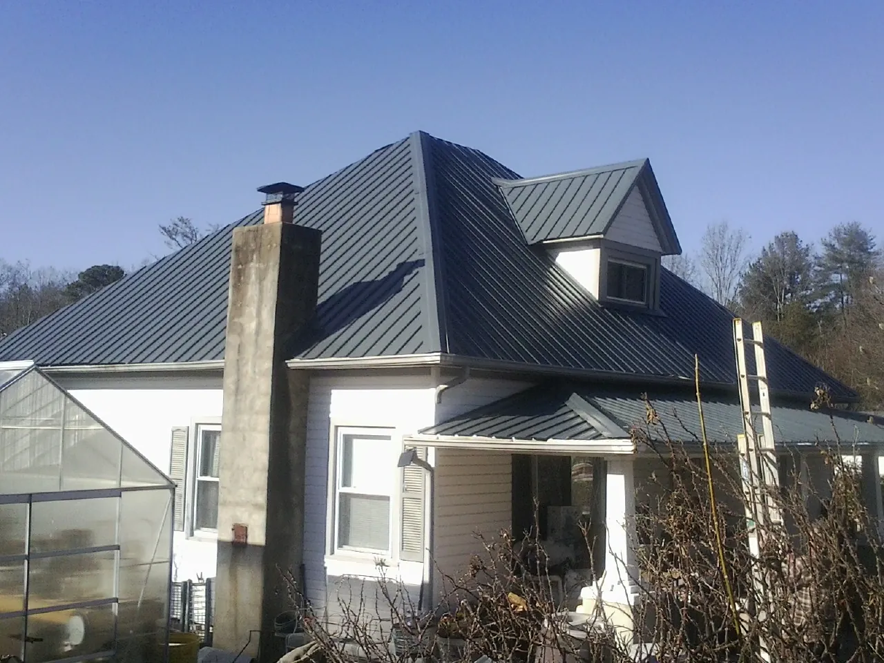 Dark blue standing seam metal roof on a white farmhouse with dormer — Slate & Tile Roof Repair by Roofing Brothers in American Fork