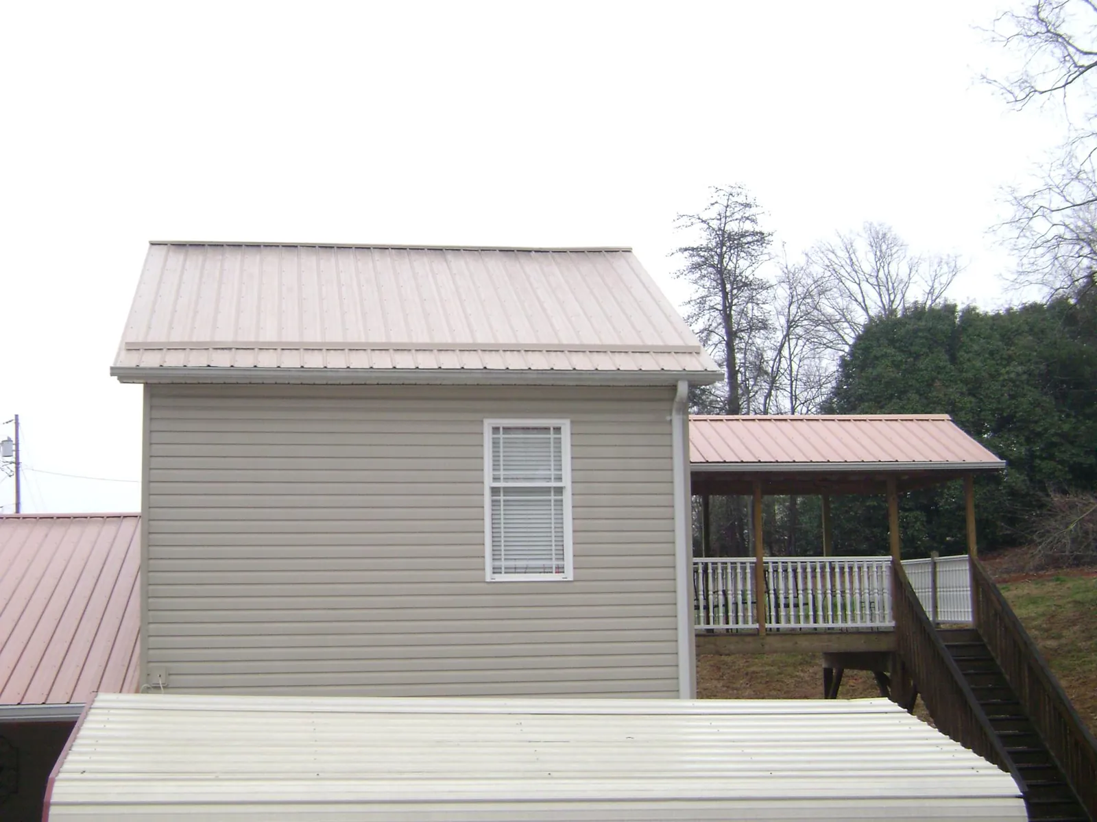 Tan metal roofs on a two story addition and attached porch, from a Roof Replacement job in American Fork