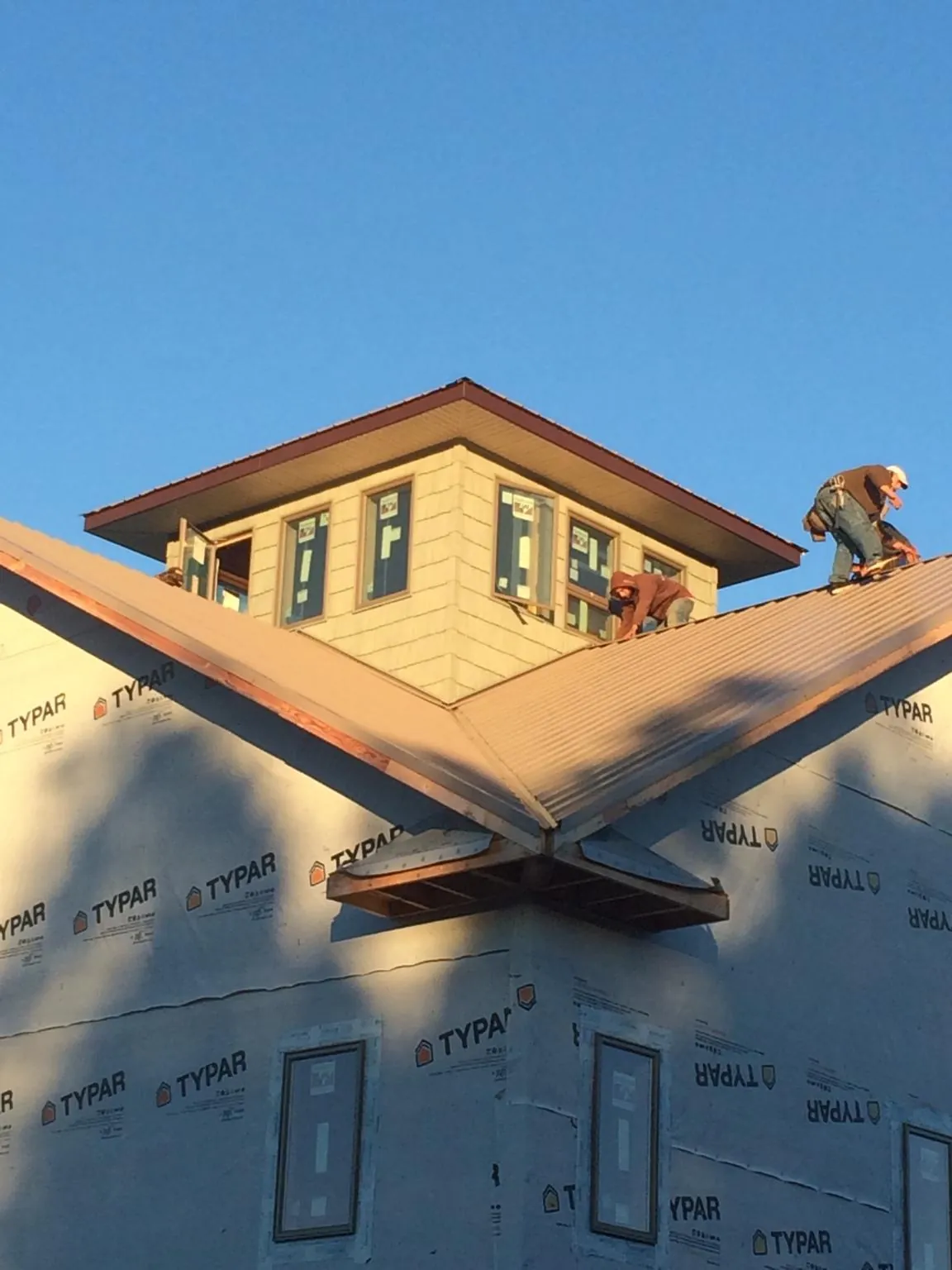 Roofers working around a rooftop cupola on a new metal roof at sunset — Roof Waterproofing in American Fork by Roofing Brothers